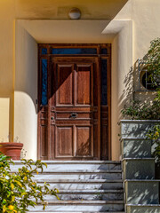 A contemporary house entrance with marble stairs and a brown wooden door. Travel to Athens, Greece.