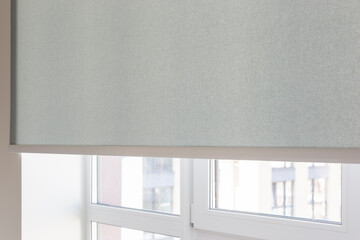 Details of gray fabric roller blinds. Automatic curtain close-up on the window. Selective focus....