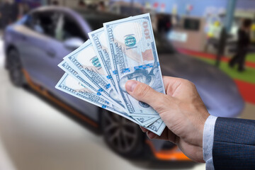 Man with 100 dollar banknotes money near car. Buy or rent a new auto. Finance concept.