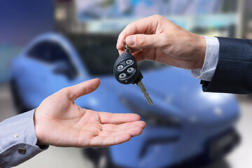 Auto business, car sale, transportation, people and ownership concept - close up of car salesman giving key to new owner or customer over auto show background.
