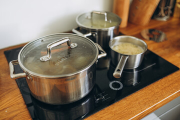 Cooking pots with tasty soup on electric stove in kitchen at the home, food concept