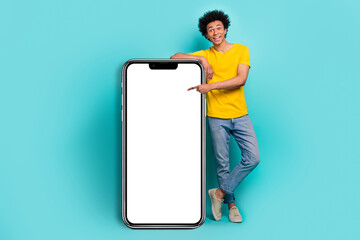 Full body length image of young promoter guy new smartphone app website point finger electronic panel advert isolated on aquamarine color background