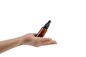 Hand and cosmetic bottles made of dark amber glass on a transparent background.