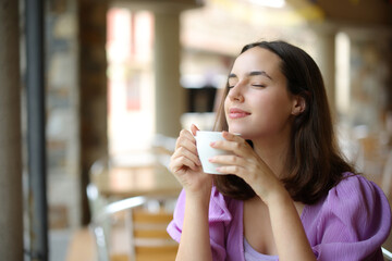 Woman relaxing smelling coffee aroma in a bar