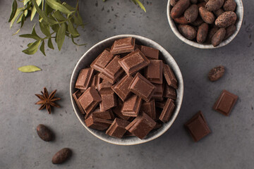 Pieces of natural milk chocolate and cocoa beans in bowls. Natural products, artisan chocolate.