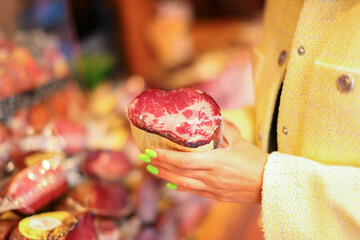 Female hand hold piece of meat in a market