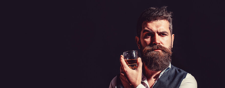 Sipping whiskey. Portrait of man with thick beard. Macho drinking. Man beard holds glass brandy. Bearded drink cognac. Man holding a glass of whisky