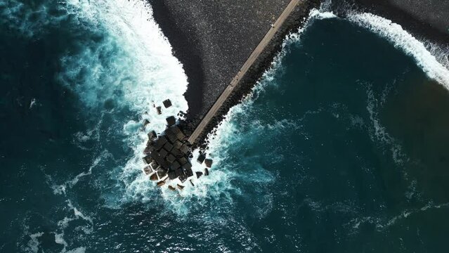 ocean blue water waves and stone breakwater with black beach, Tenerife, Canary