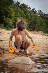 A boy was playing with sand on the seashore. A child was playing with sea sand on the sandy shore of the sea. Soft selective focus