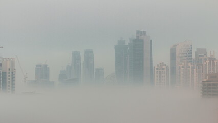 Dubai skyscrapers with morning fog in business bay district night to day timelapse.