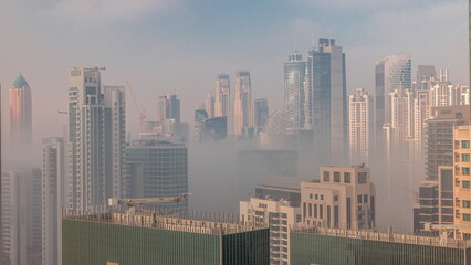 Fototapeta na wymiar Dubai skyscrapers covered by morning fog in business bay district during sunrise timelapse.