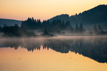 Fototapeta na wymiar lever de soleil et brume matinale sur le lac de Lamoura dans le Haut Jura en France