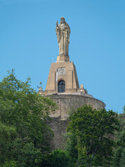 Naklejka premium Jesus statue over San Sebastian. Dominating the top of the Urgull hill is this Sacred Heart Christ statue overlooking San Sebastian. Blue sky background.