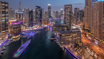 Aerial view to Dubai marina skyscrapers around canal with floating boats day to night timelapse