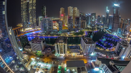 Panorama of Dubai Marina with several boat and yachts parked in harbor and skyscrapers around canal aerial all night timelapse.
