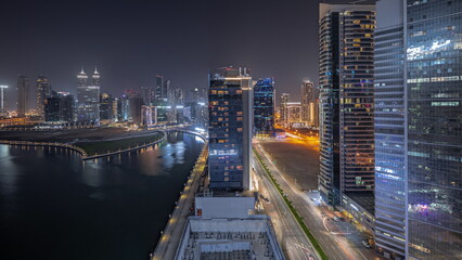 Panorama showing cityscape of skyscrapers in Dubai Business Bay with water canal aerial night timelapse
