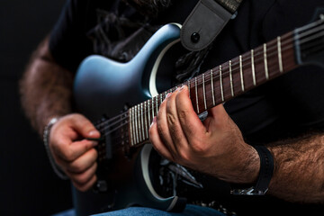 Brutal man's hands of the musician play the electric guitar. Hobby, passion and creativity. Close-up.