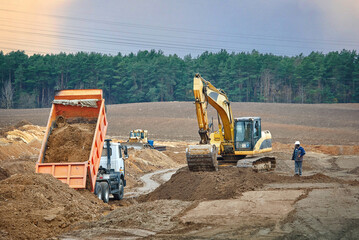 Dump truck unload sand, excavator digging trench and bulldozer leveling ground at construction...