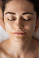 Close-up of a woman lying on a massage table with her eyes closed getting ready for procedures. Spa skin and body care. Facial beauty treatment. Cosmetology.