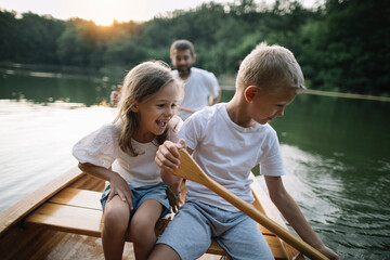 Kids learning to paddle canoe with their dad