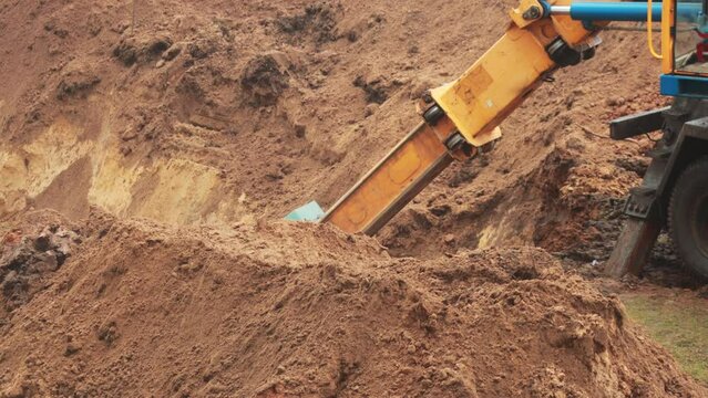 An auto excavator with a retractable and swivel bucket digs a hole to replace the pipeline. Industry