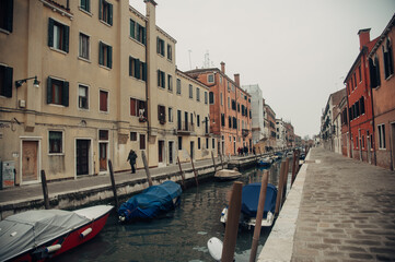 Obraz na płótnie Canvas A serene Venice canal with boats tied to posts, lined by charming sidewalks on each side.