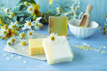 Obraz na płótnie Canvas Soap with chamomile, bouquets of fresh chamomile flowers and sea salt, on a wooden background, natural cosmetics, body care and bath products