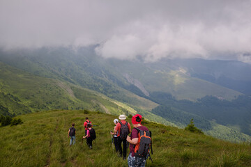 Obraz premium Back view of group tourists in mountains. Hiking with the group. Active lifestyle, sport and tourism. 