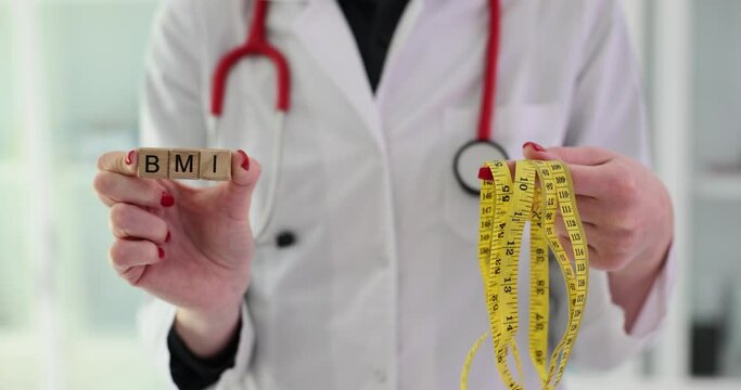 Doctor holds word BMI from wooden blocks and measuring tape to measure standing in clinic office. Body mass index and device for measuring parameters