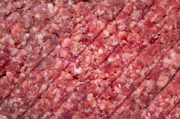 Juicy raw burger patty against a dark backdrop.