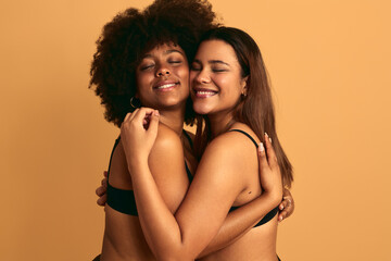 Cheerful multiethnic women hugging with closed eyes