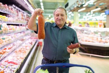 Older man picking out sausage to buy in grocery store