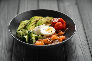 Balanced diet, cooking, culinary and food concept. Ketogenic diet breakfast. Salt salmon salad with avocado, sesame, tomato, cucumber and quail egg.