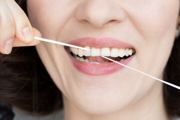 Woman brushing her teeth with dental tape close-up. Small distance between teeth