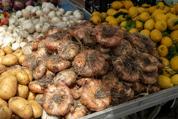Beautiful arge italian raw onions (translation cipolla), potatoes, lemons and garlic sold at an Italian market in Sicily