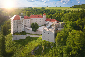 Traveling Poland castle concept: Panoramic Aerial view of Pieskowa Skała Renaissance castle, standing on Little Dog's Rock  limestone cliff in the green forest valley of river Prądnik. Summer, sunset.