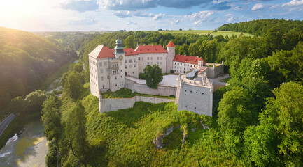Traveling Poland: Panoramic Aerial view of Pieskowa Skała Renaissance castle, standing on Little Dog's Rock  limestone cliff in the green forest valley of river Prądnik. Summer, sunset.