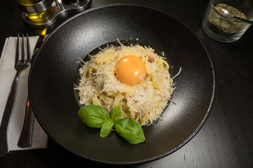 A bowl of spaghetti carbonara with an egg yolk.