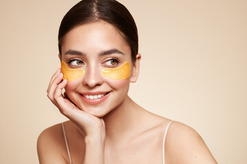 A young beautiful smiling woman with cosmetic patches on her eyes. Cosmetic procedures skin care...