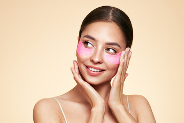 A young beautiful smiling woman with cosmetic patches on her eyes. Cosmetic procedures skin care...