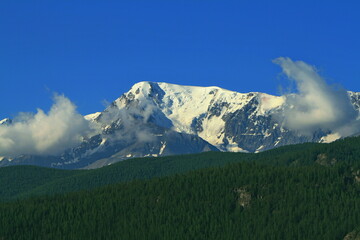 Fototapeta premium Aktash, Altai Republic, Russia - July 01, 2022: View of the green forest mountains with icy peaks