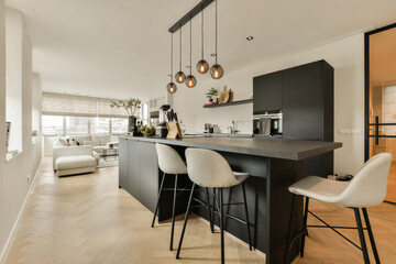 a kitchen and dining area in a modern apartment with white walls, hardwood flooring and black...
