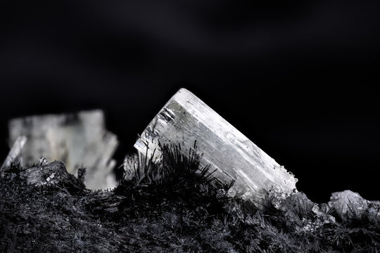 goshenite (colorless beryl) on schorl (black tourmaline) matrix. macro detail texture background. close-up raw rough unpolished semi-precious gemstone with black background