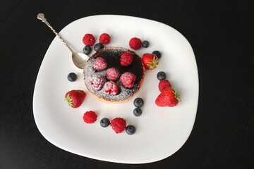 cream cake with raspberries and blueberries and small macaroons served on a large white plate