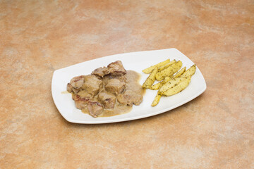 A platter of tender sirloin medallions smothered in a rich cabrales cheese sauce, served with crispy potato wedges seasoned with garlic and thyme, on a rustic kitchen countertop. Traditional food.