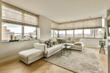 a living room with wood flooring and white couches in front of large windows looking out onto the city