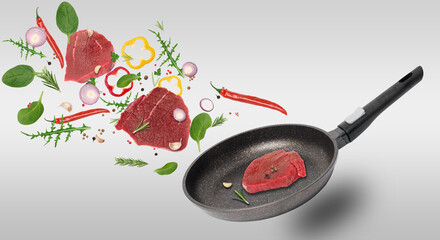 Empty black frying pan, beef steaks, spices and rosemary leaves levitate. Cooking steak with vegetable