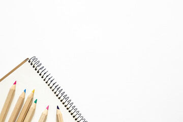 Fototapeta premium Wooden pencils of different colors and a notebook on a white background.