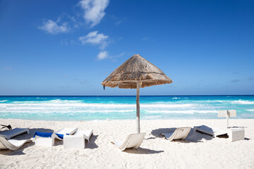 Caribbean sea coastline with grass sun umbrella and wooden beach beds