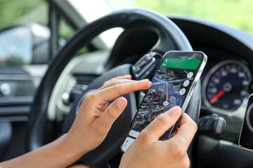 Female driver hand holding a phone with interface navigator on a screen.